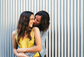 Affectionate woman kissing her happy girlfriend smiling, same sex relationship concept.