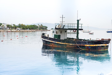 Naklejka premium Old rusty fishing boat on the Aegean Sea, moored to the shore, Turgutreis Turkey