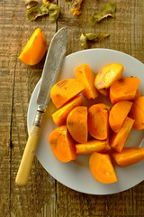 Some khaki fruits in a basket over a wooden surface, top view.