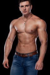 Fototapeta premium Bodybuilding competitions on the scene. Man sportsmen physique and athlete. Black background with lights.