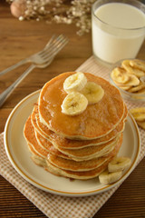 Stack of pancakes with banana slices and honey, on wooden background. Homemade american pancakes, isolated.