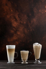 Three cups of coffee at wooden table background. Vertical image with free space.