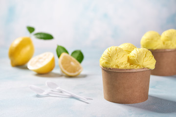 two portions lemon ice cream in paper cup on mint colors background, top view