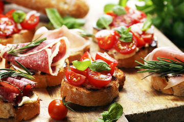 antipasto various appetizer. Cutting board with prosciutto, salami, cheese, bread and olives on dark wooden background