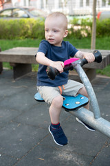 Child playing on outdoor playground in summer. Kids play on kindergarten yard. Active kid on colorful swing. Healthy summer activity for children in summer. Little boy swinging.