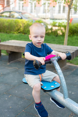 Child playing on outdoor playground in summer. Kids play on kindergarten yard. Active kid on colorful swing. Healthy summer activity for children in summer. Little boy swinging.