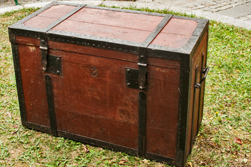 Old vintage retro wooden chest with iron strapping on green grass house backyard