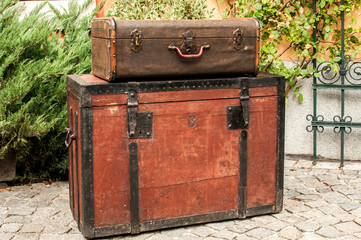 Old retro wooden chest and vintage grunge suitcase isolated on stone paved house backyard