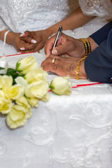 vertical orientation close up of bride and groom signing marriage license documents during wedding ceremony 