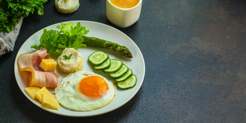 breakfast - fried eggs, lettuce, lettuce, cucumbers, asparagus, bacon, sauce and more. top. food background. space for text and lettering