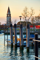 Venice, Italy. Sunset evening. View at tower and Pier and landing with boat at water. Autumn landscape.