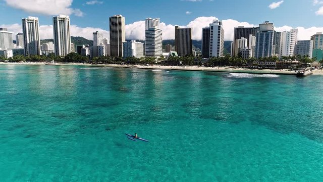 Flying towards the beach and skyline, over rower chilling in the water.