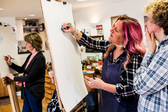 Woman standing at an easel, drawing a human leg at a life drawing glass.