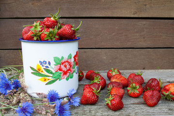 Czerwone truskawki w białym malowanym garnku © Monika
