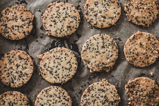 High angle close up of freshly baked seeded crackers on a baking tray.