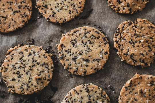 High angle close up of seeded cracker dough on a baking tray.