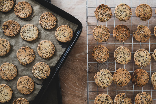 High angle close up of freshly baked seeded crackers on a baking tray.