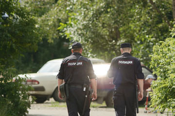 Two russian policemans patrols street of provincial town. Two mans in police uniform go in direction of russian cars. Inscription 