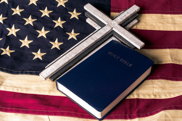 wood cross and blue bible on old looking tea stain american flag - Powered by Adobe