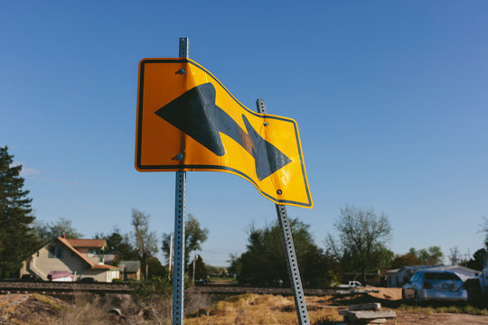 A bent old two arrow road side, arrows pointing in two different directions. ,Road sign