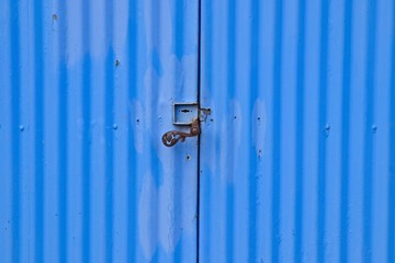 A blue corrugated iron door with a vintage steel handle. 