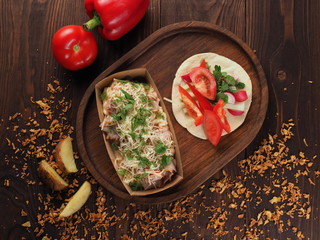 Fried pork with cheese, macaroni and dill in a paper container