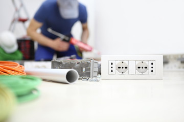 electrician at work with silicone gun in hand, install socket, electric circuits, electrical wiring