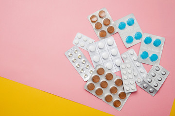 lot of pink medicine pills. Medicine pills blister packs pile, different colors, yellow background. Drug prescription for treatment medication. Antibiotic painkiller.