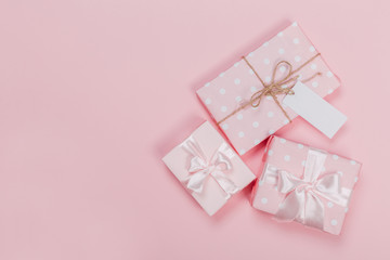 Gift box wrapped in pastel  paper with pink ribbon on pink surface. Top view  and  with copy space.