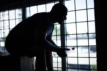 silhouette of an athlete who is resting sitting with a bottle of water in the cube. in front of...