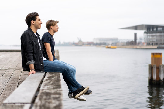 Denmark, Copenhagen, two young men sitting at the waterfront