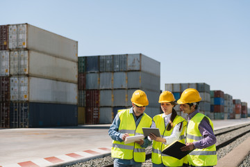 Workers at railway tracks near cargo containers on industrial site