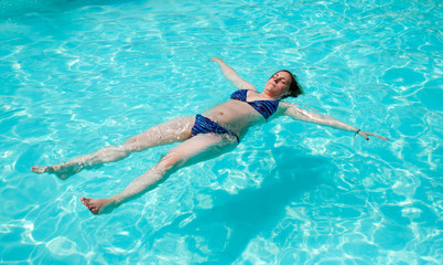 Woman lying on the surface of the water in the pool.