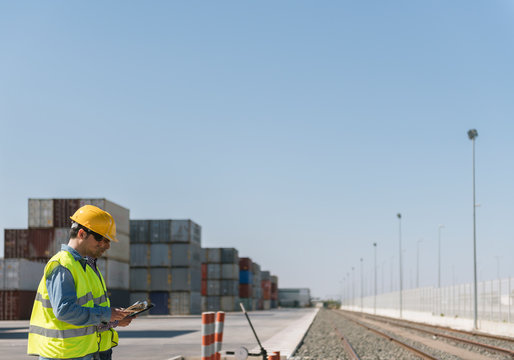 Workers in front of cargo containers near railway tracks on industrial site