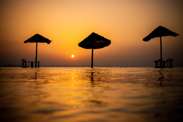 Mediterranean sea, beach umbrellas, sunset.