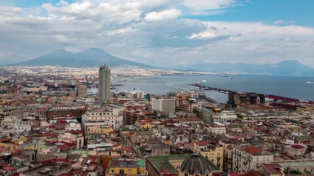 Napoli, Campania, Italy: time lapse boats enter the port with clouds, aerial view of Naples with landmarks of the city, the Maschio Angioino, the port and Vesuvius in the background