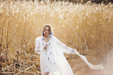 Portrait of young beautiful girl in the white dress in wheat field, walking, carefree. Enjoying the beautiful sunny day