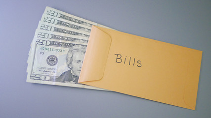 A yellow envelope on a gray table, containing cash for personal bills.