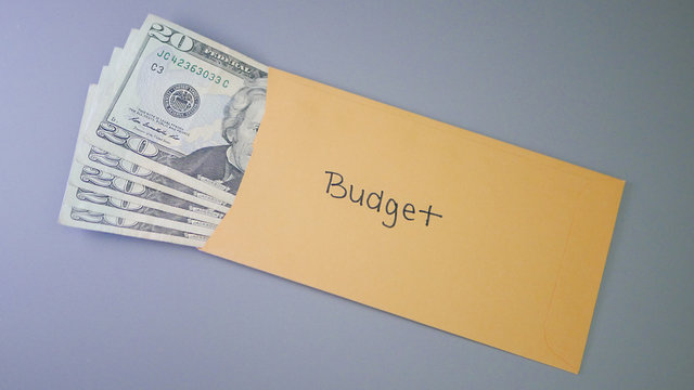 A yellow envelope on a gray table, containing cash for personal budget.