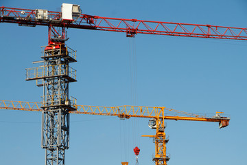 Two Construction cranes tower on blue sky background. Crane and building working progress. Empty Space for text.