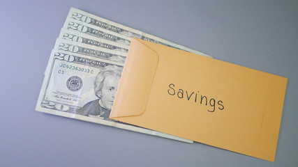 A yellow envelope on a gray table, containing cash for savings.