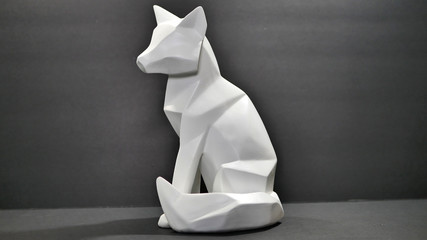 An angle cut polygon wood fox or wolf animal figure statue, painted white on a black background.