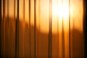 Golden sunlight shining through textured curtain.  