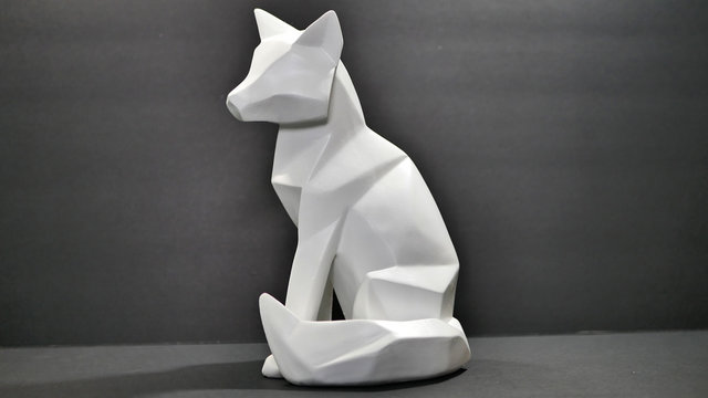 An Angle Cut Polygon Wood Fox Or Wolf Animal Figure Statue, Painted White On A Black Background.