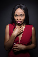 Portrait of a Black African American female wearing a red outfit on a dark background.  She looks...