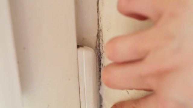 A woman's hand runs along the old dirty window slope. Show black mold Aspergillus closeup. Real time, contains people, natural light
