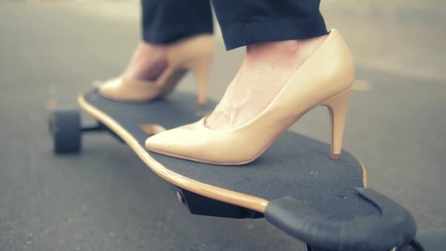 close-up. women's beige shoe on a black skate board. Modern business woman in beige pumps shoes, rides on an electric board along a city street. The concept of achieving the goal and leadership