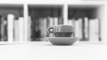 Black and white cup of coffe on table in backgrund are blurred books