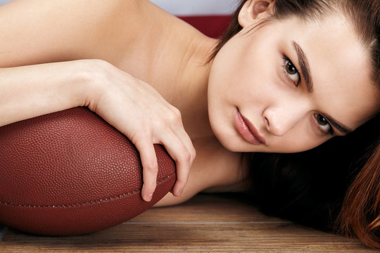 Closeup portrait of naked beautiful adult girl with american football ball. American football sport concept