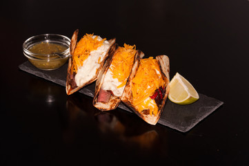 Mexican food. Taco - Steak with fried onions, cheddar cheese, salsa verde sauce and jalapeno mayonnaise